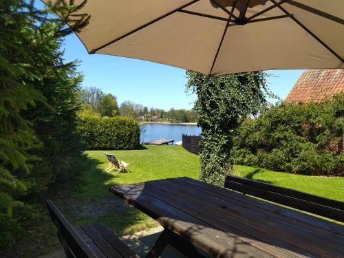 a picnic table with an umbrella next to a lake at Apartamenty 47 in Dorotowo