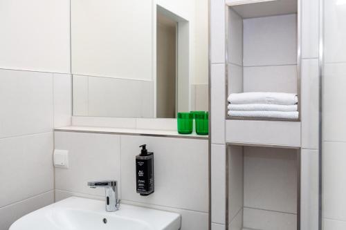 Un baño blanco con lavabo y espejo. en Hotel Fuchsbau Jüterbog, en Jüterbog
