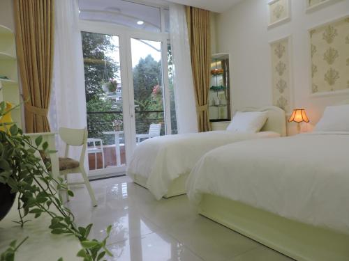 a white bedroom with two beds and a balcony at Chez Lotus Rose in Ho Chi Minh City