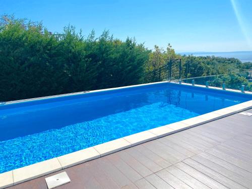 een groot blauw zwembad met een houten terras bij Apartment Flora with swimming pool in Kastav
