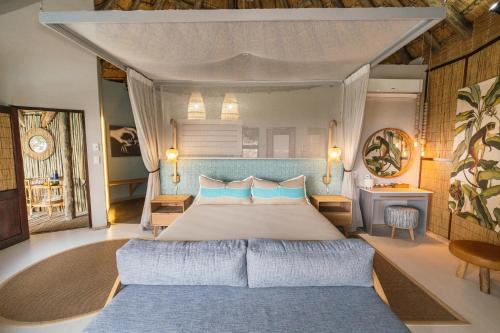 a bedroom with a large bed with blue pillows at Thonga Beach Lodge in Mabibi