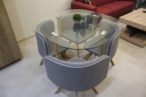 a glass table and chairs with a potted plant on top at Oualidia City Centre Cosy Apartment, Free WIFI in Oualidia