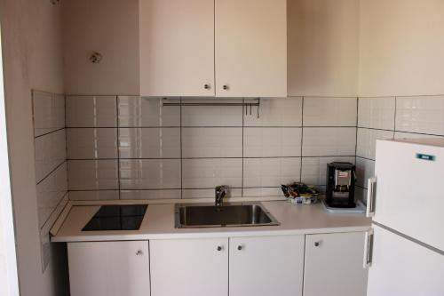 a kitchen with white cabinets and a sink and a refrigerator at Casa Vacanze "A Machina Ro Ghiaccio" in Noto