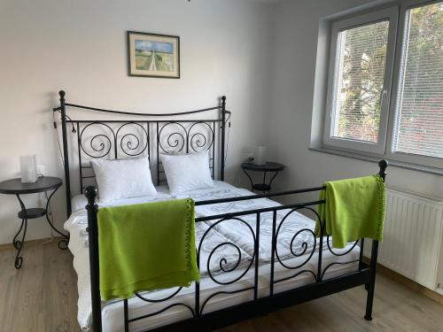 a bedroom with a black bed with green towels on it at Apartments Rose in winter in Bled