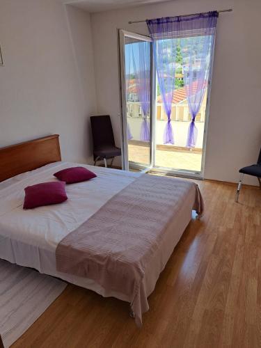 a bedroom with a large bed and a large window at Apartments Andelic in Vinišće