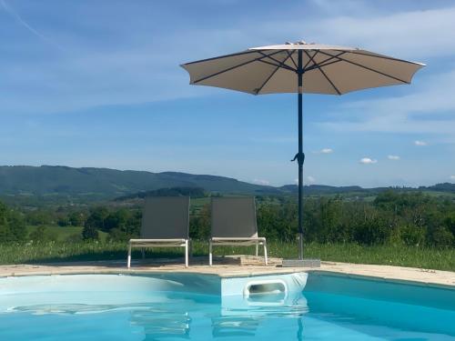 einen Pool mit 2 Stühlen und einem Sonnenschirm in der Unterkunft Château de Vaux 