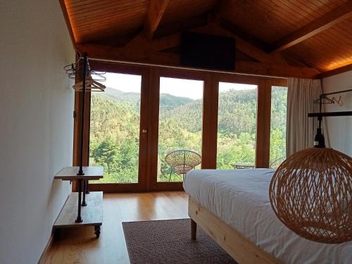 a bedroom with a bed and a large window at Moinhos do Paiva in Castelo de Paiva