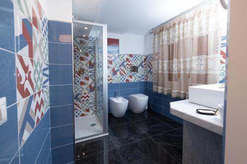 y baño de azulejos azules con ducha y lavamanos. en B&b Essence Ispica, en Ispica