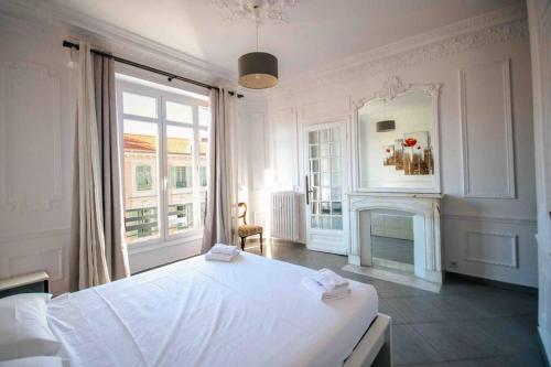 a white bedroom with a large bed and a fireplace at Sublime 4 pièces quartier des Musiciens in Nice