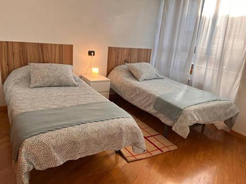 a bedroom with two beds and a lamp on a wooden floor at VibesCoruna - Rios 6 in A Coruña