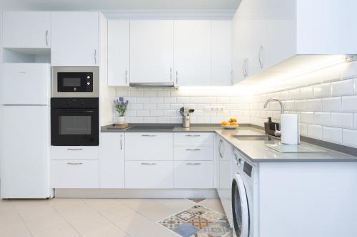 a white kitchen with white cabinets and a dishwasher at Home2Book Casa Malena Tabaiba Seaview in Tabaiba