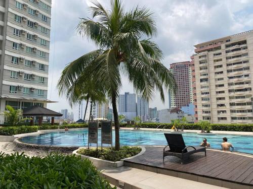 a palm tree and a chair next to a swimming pool at Makati Penthouse with Stunning City Skyline View in Manila