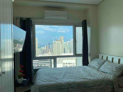 a bedroom with a bed and a large window at Makati Penthouse with Stunning City Skyline View in Manila