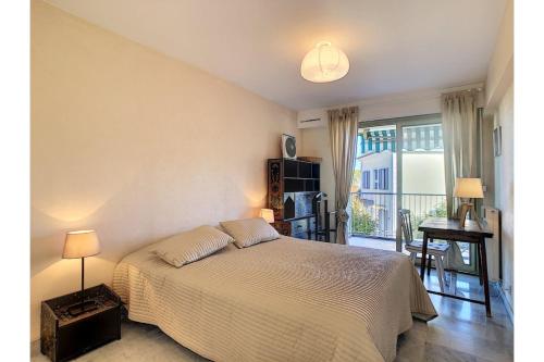 Schlafzimmer mit einem Bett, einem Schreibtisch und einem Fenster in der Unterkunft L'Ermitage - Happy Rentals in Antibes