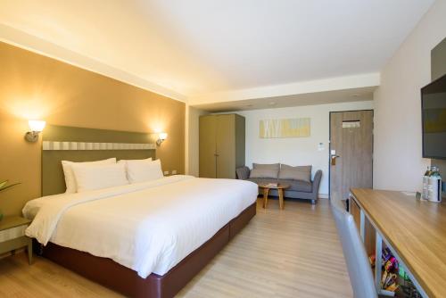a hotel room with a large bed and a couch at SC Park Hotel in Bangkok