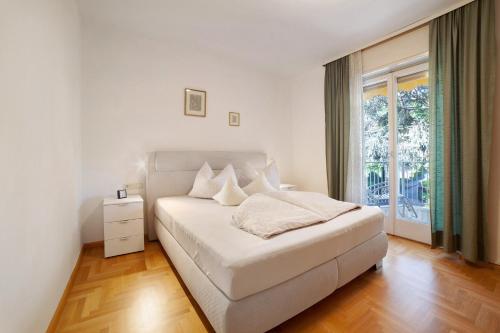 um quarto branco com uma cama e uma janela em Villa Sabine - Karin em Merano