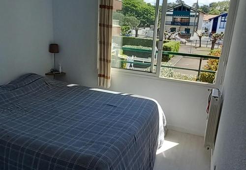 Un dormitorio con una cama azul y una ventana en Appartement bord de mer très lumineux 2/4 pers. - Vue inoubliable en Hendaya