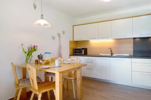 a kitchen with a wooden table and white cabinets at Stiflerhof Apt Enzian in Falzes
