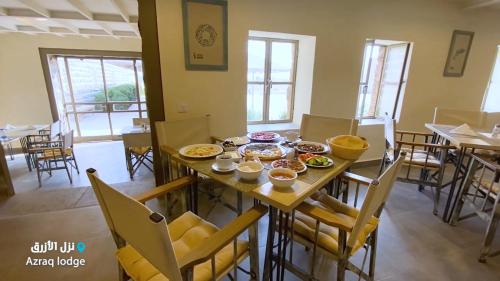 Al Azraq ash ShamālīAzraq Lodge的用餐室配有餐桌和食物