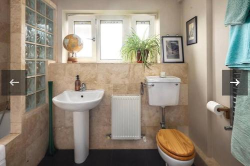 łazienka z umywalką, toaletą i oknem w obiekcie Flat by Victoria park - with balcony w Londynie
