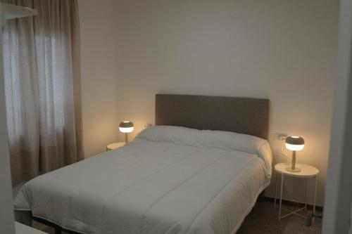 ein Schlafzimmer mit einem weißen Bett mit zwei Tischen und zwei Lampen in der Unterkunft Roses Center 6 in Roses