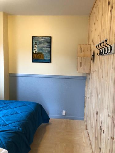 Un dormitorio con una cama azul y una pared en Chalets les chanterelles de Forillon, en L’Anse-au-Griffon