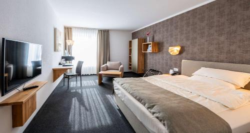 a hotel room with a bed and a flat screen tv at Best Western Plus iO Hotel in Eschborn