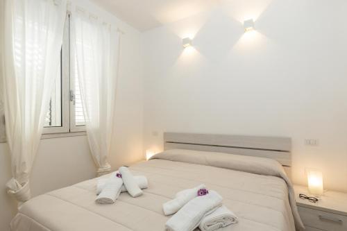 um quarto branco com toalhas numa cama com uma janela em Melania Holidays Home - Sole Incantatore em Santa Maria Navarrese
