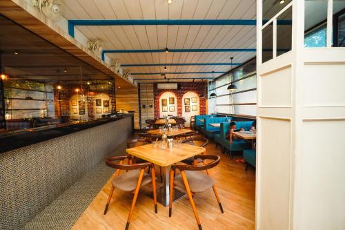un restaurante con mesas de madera y sillas azules en Cygnett Inn Celestiial Goa, en Candolim