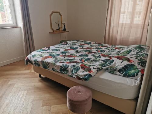 ein Bett mit einer bunten Bettdecke und einem Hocker im Schlafzimmer in der Unterkunft LE PETIT ANGLE APPARTEMENT 2 Pièces, plein centre ville, près de la gare jusqu'à 4 personnes in Bellegarde-sur-Valserine