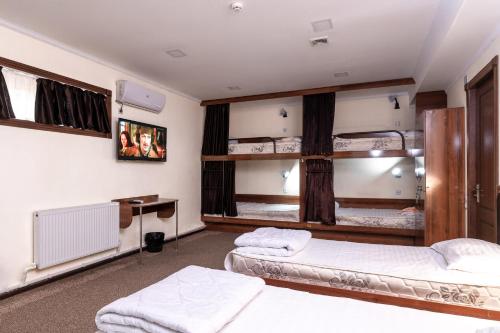 a room with two beds and a desk in it at Hostel makon in Kirgili