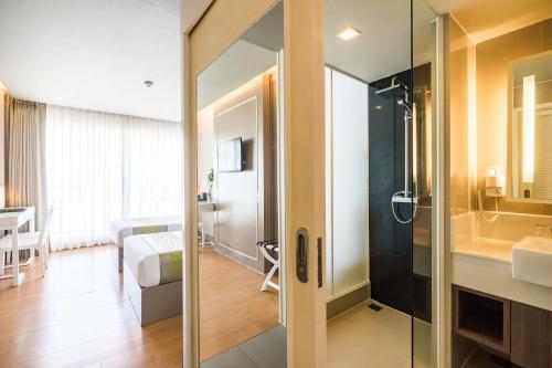 a bathroom with a shower and a sink and a bedroom at Best Western Patong Beach in Patong Beach