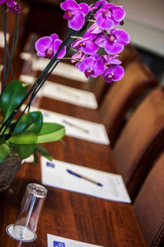 a vase of purple flowers on a wooden table at Garden Court Morningside Sandton in Johannesburg