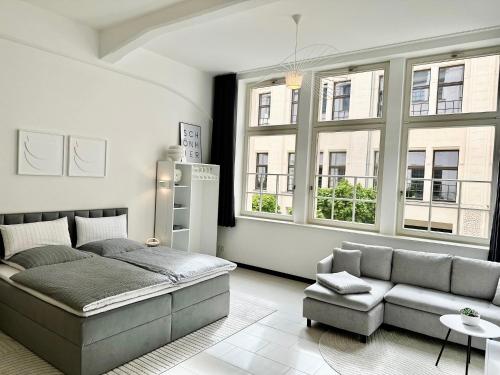 a bedroom with a bed and a couch and windows at MEOS 2 -Zentrum-Hofblick-Gym-Netflix in Leipzig