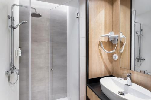 a bathroom with a shower and a sink and a mirror at B&B HOTEL Guimarães in Guimarães