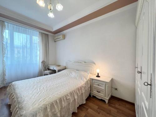 um quarto branco com uma cama e uma janela em Apartments near Arena City em Kiev