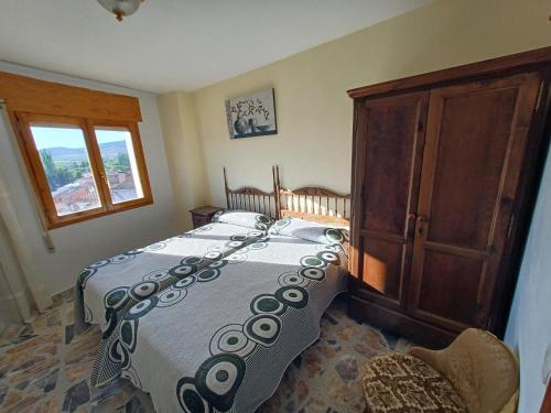 a bedroom with a bed and a wooden cabinet at Casa Rural Sol y Luna Apartamentos in Munébrega