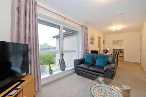 a living room with a couch and a large window at Caledonia Newhills Apartment in Aberdeen