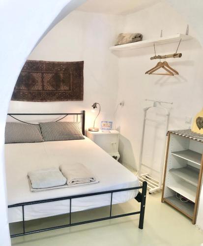 a white bedroom with a bed and a shelf at Sunset House in Serifos Chora