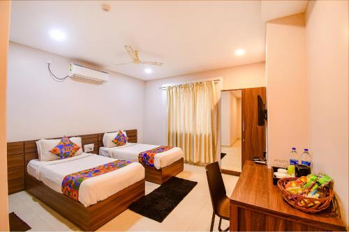 a hotel room with two beds and a desk at FabHotel Royal Crystal in Bhubaneshwar