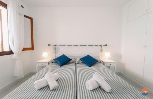 Un dormitorio con una cama con almohadas azules y blancas. en Aldeas Taray Admer 003, en La Manga del Mar Menor