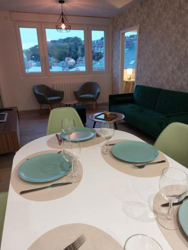 - une salle à manger avec 2 tables, des assiettes et des verres à vin dans l'établissement Sur les toits de Dieppe, à Dieppe