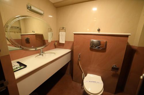 a bathroom with a sink and a mirror and a toilet at HOTEL UDUPI INTERNATIONAL in Nāgercoil