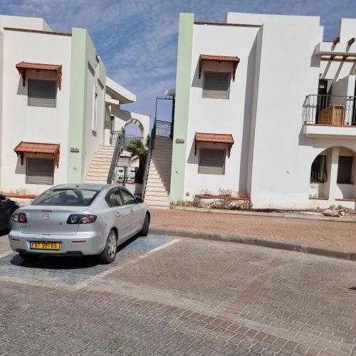 a car parked in a parking lot in front of some buildings at Daniel's garden apartment in Eilat