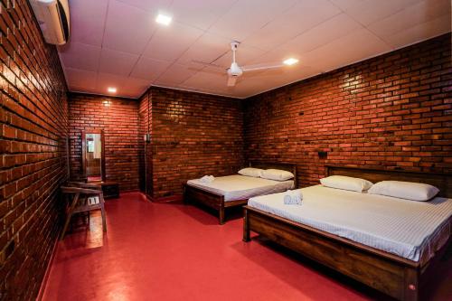 a room with two beds and a brick wall at River Inn - Fort in Matara