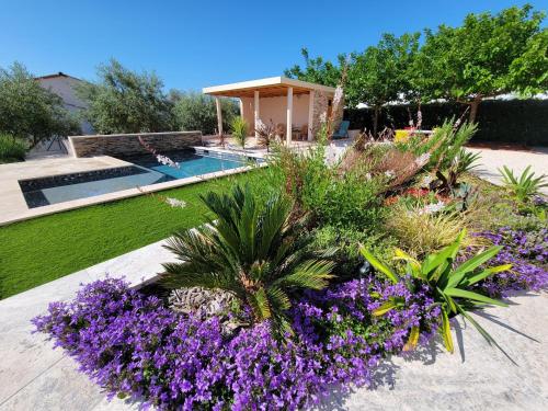 un jardin avec des fleurs violettes et une piscine dans l'établissement Villa Tropez Chambres d'hôtes, au Luc