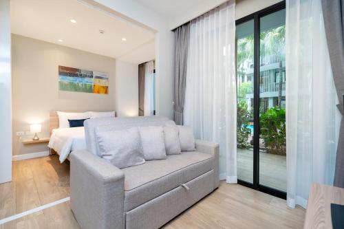 a bedroom with a bed and a chair and a window at Pool Access Condo Bangtao Beach in Bang Tao Beach