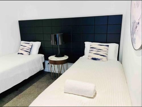 una camera con due letti e un tavolo con una lampada di Chatswood Exeutive Suites - 3beds2baths a Sydney