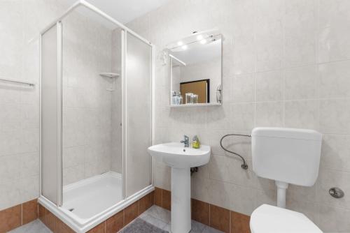 baño blanco con ducha y lavamanos en Apartments Morena, en Novigrad Istria