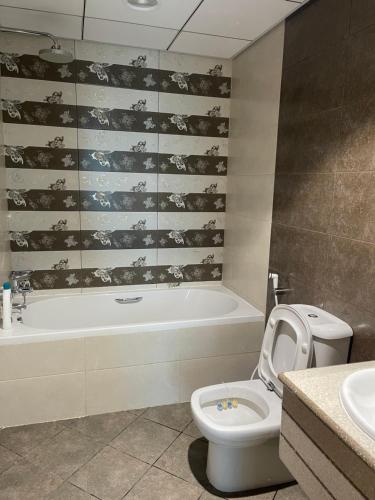 a bathroom with a tub and a toilet and a sink at Lovely 2 BHK just 2 min from the beach in Ajman 
